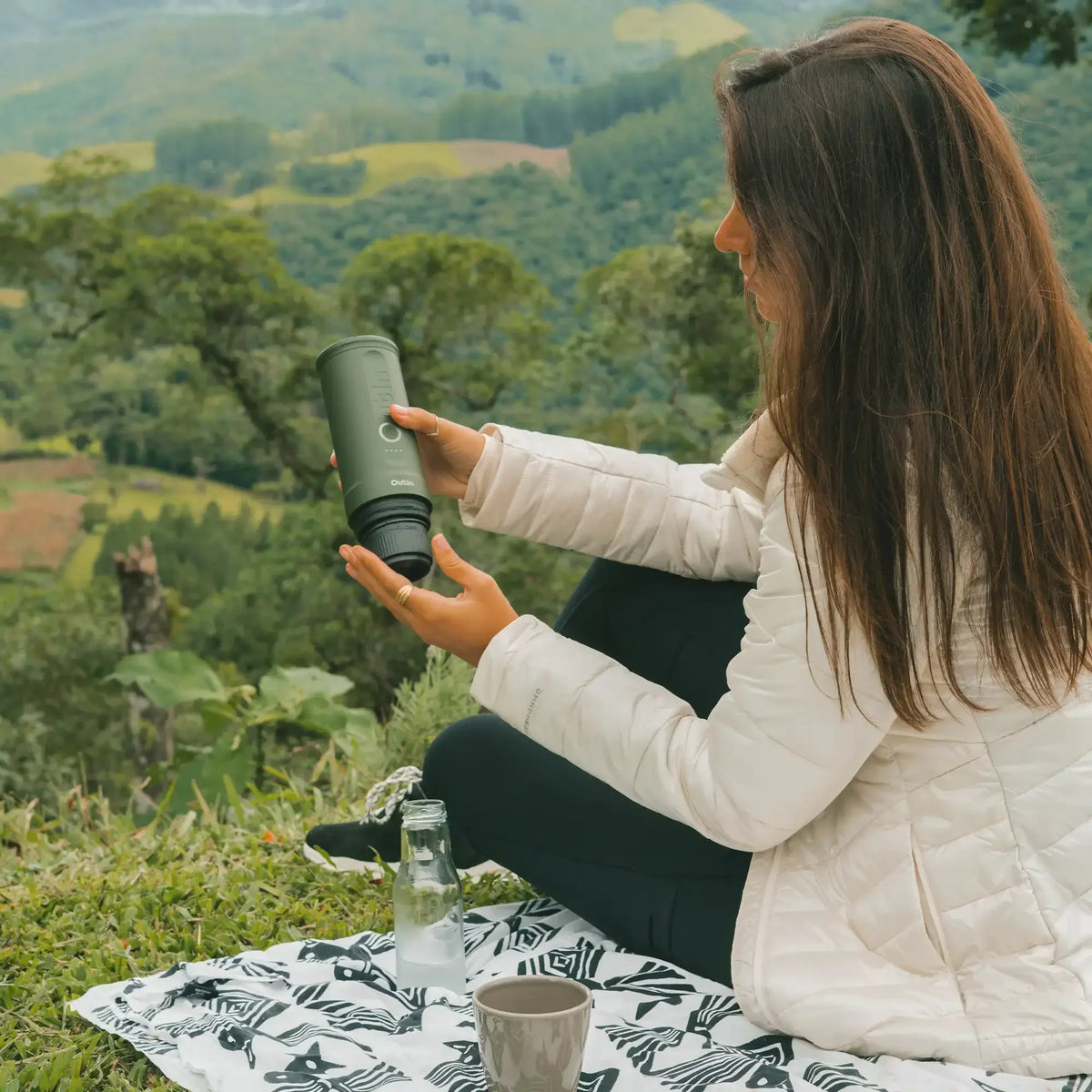Outin Nano portable espresso machine in Forest Green with ground coffee, coffee capsules and a glass of espresso