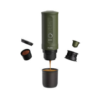 Outin Nano portable espresso machine in Forest Green with ground coffee, coffee capsules and a glass of espresso