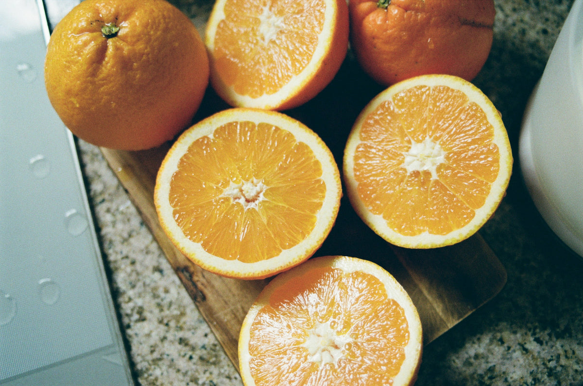Whole and halved oranges on a wooden chopping board