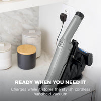 Shark WandVac Deluxe Pet Pro Stone Grey charging on its storage base plugged into a wall socket, captioned 'Ready when you need it'