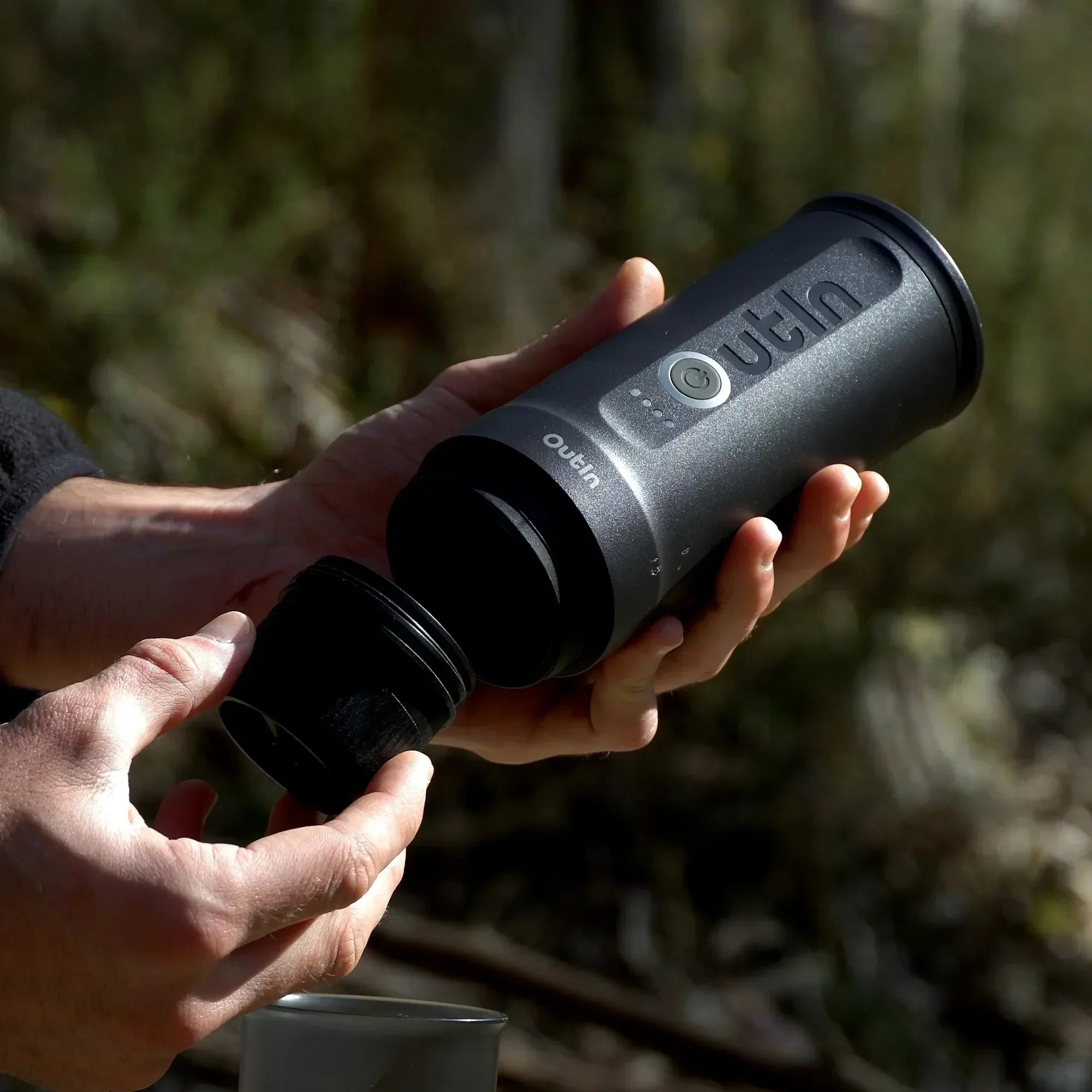 Outin Nano portable espresso machine in Space Grey with ground coffee, coffee capsules and a glass of espresso
