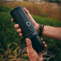 Outin Nano portable espresso machine in Space Grey with ground coffee, coffee capsules and a glass of espresso