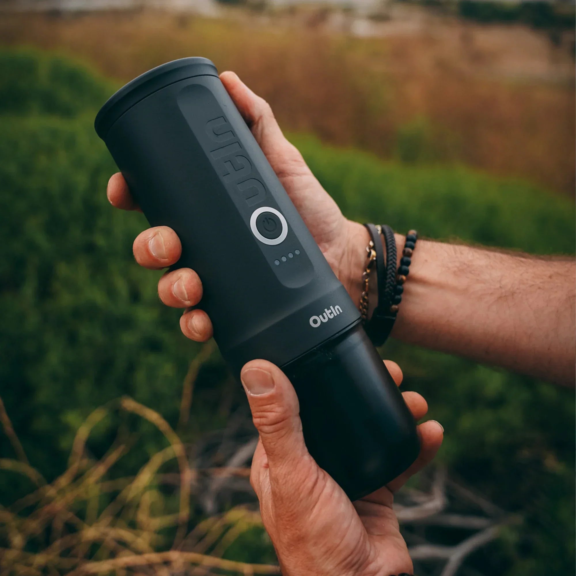 Outin Nano portable espresso machine in Space Grey with ground coffee, coffee capsules and a glass of espresso