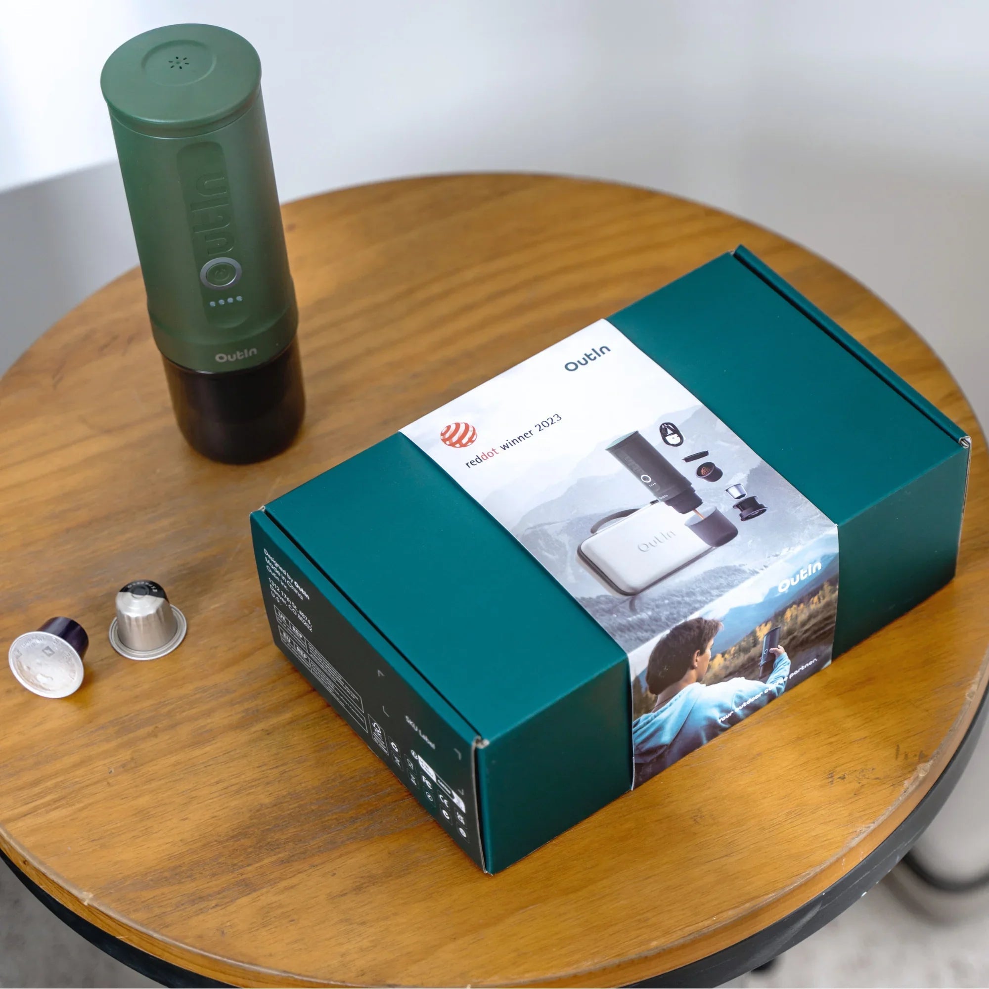 Outin Nano Forest Green portable espresso machine beside its Nano Protective Case with capsule storage