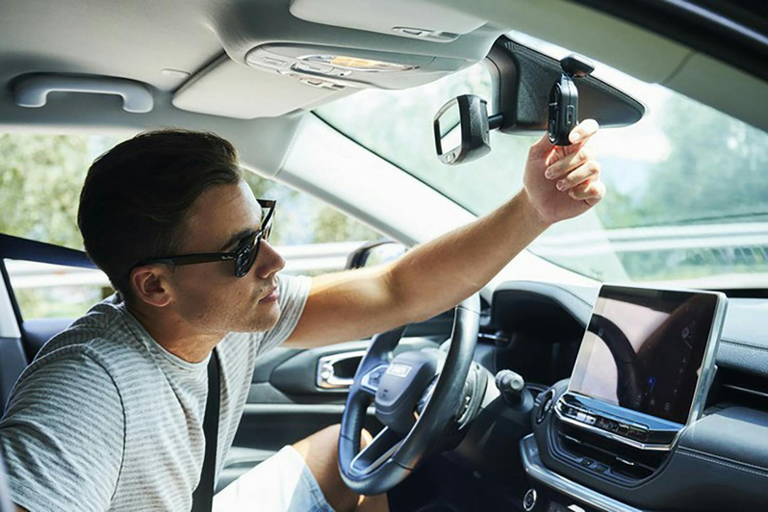 Nextbase Piqo 1K dash cam being fitted behind a rear-view mirror