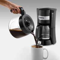De'Longhi ICM Series Filter Coffee Maker - Black - pouring coffee from the glass carafe into a mug