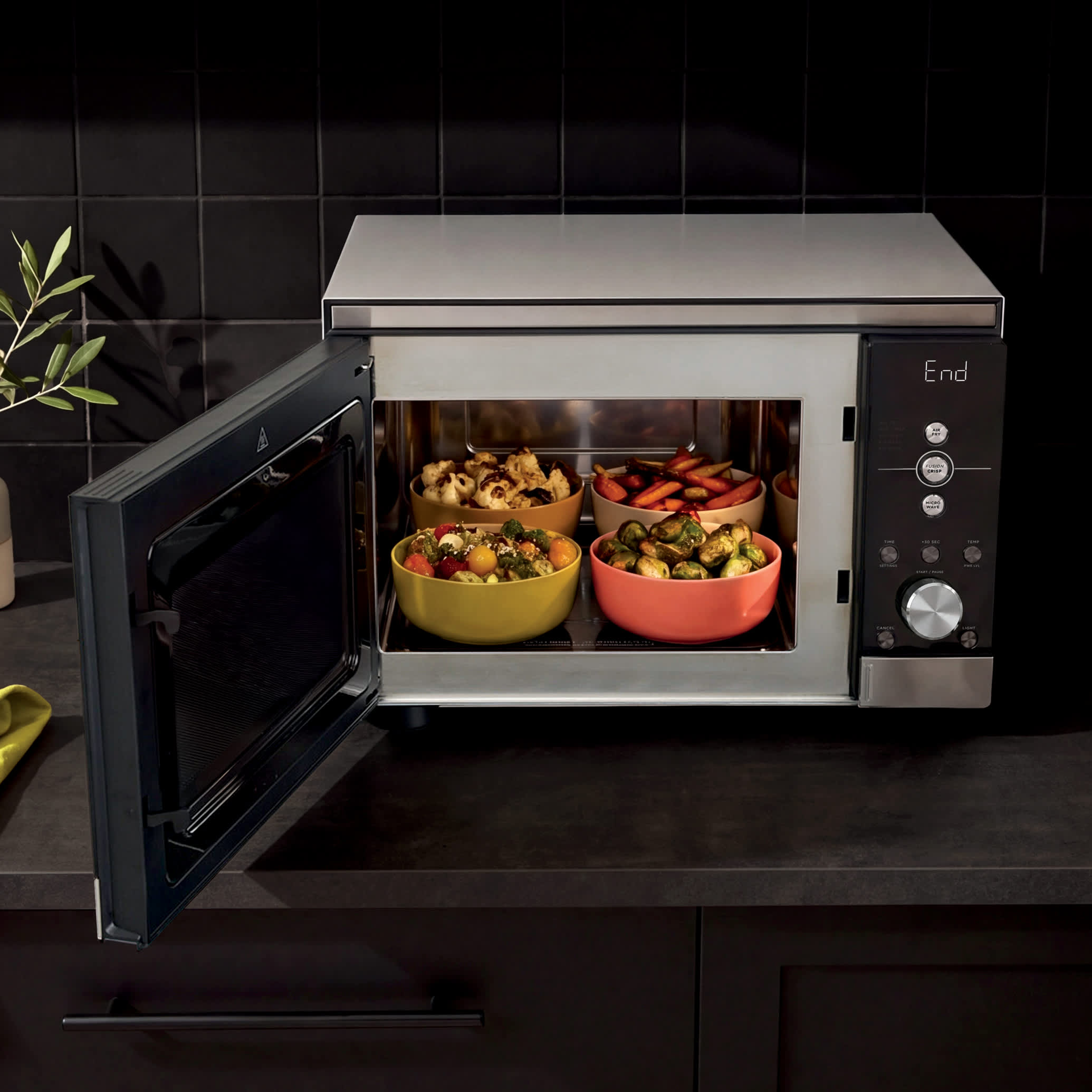Ninja CRISPi microwave in Silver, door open on dark kitchen counter with bowls of food inside