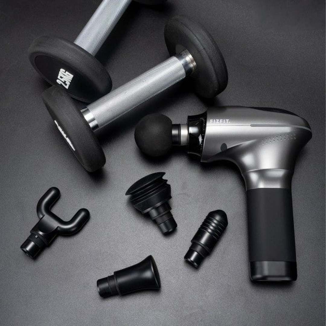 FIZFIT Massage Gun Elite 2 490278 with attachment heads and dumbbells on a dark surface