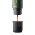 Outin Nano portable espresso machine in Forest Green with ground coffee, coffee capsules and a glass of espresso