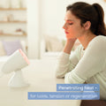 Beurer IL 11 Infrared Lamp 100W in use, woman warming face at table
