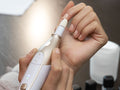 Beurer MP 64 Cordless Manicure/Pedicure device in use on hand, gold and white body
