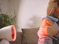 Beurer IL 35 Infrared Lamp in use on shoulder, red heat glow visible