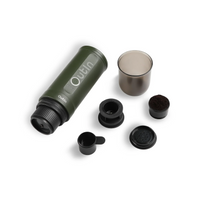 Outin Nano portable espresso machine in Forest Green with ground coffee, coffee capsules and a glass of espresso