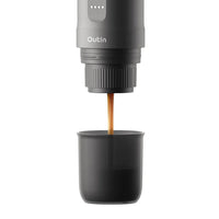 Outin Nano portable espresso machine in Space Grey with ground coffee, coffee capsules and a glass of espresso