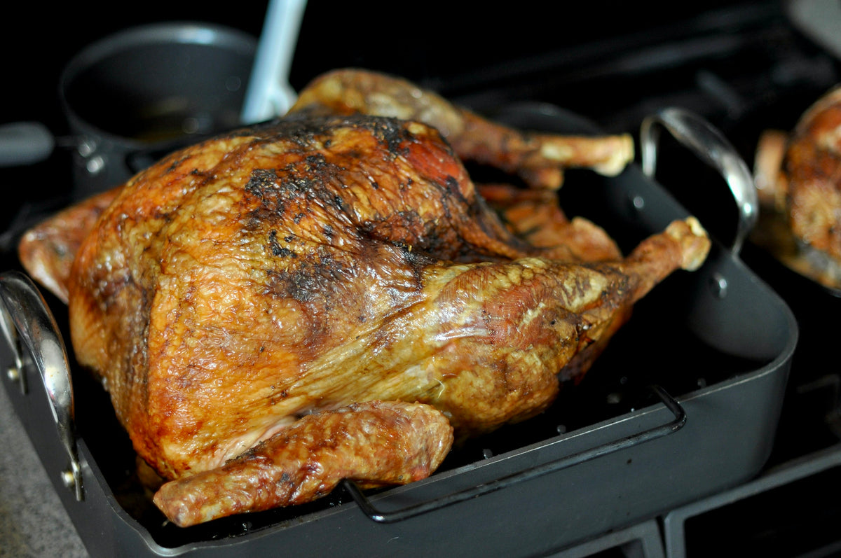 Roast turkey in a dark roasting pan on a hob