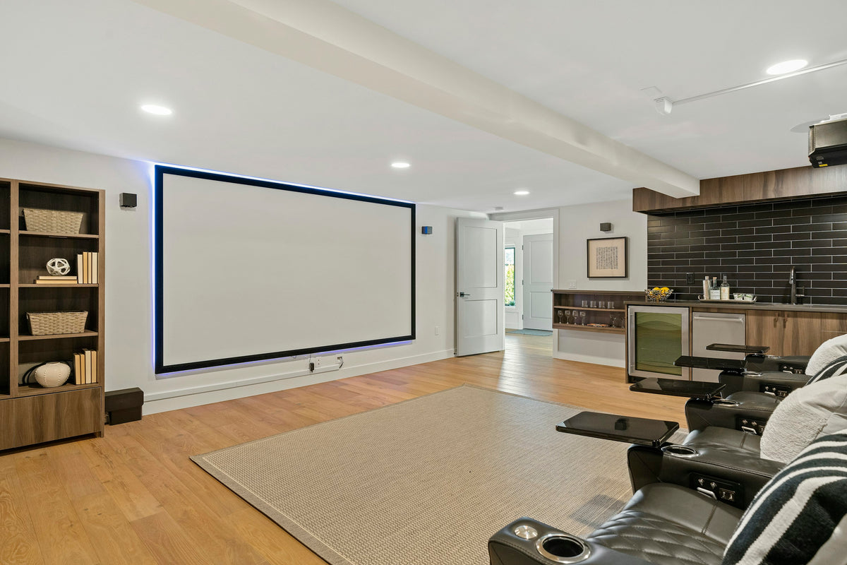 Living room with a large blank projection screen on the wall and a ceiling projector