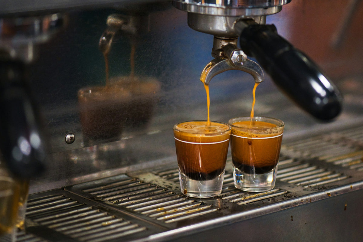 Two shots of espresso pouring into small glasses on an espresso machine