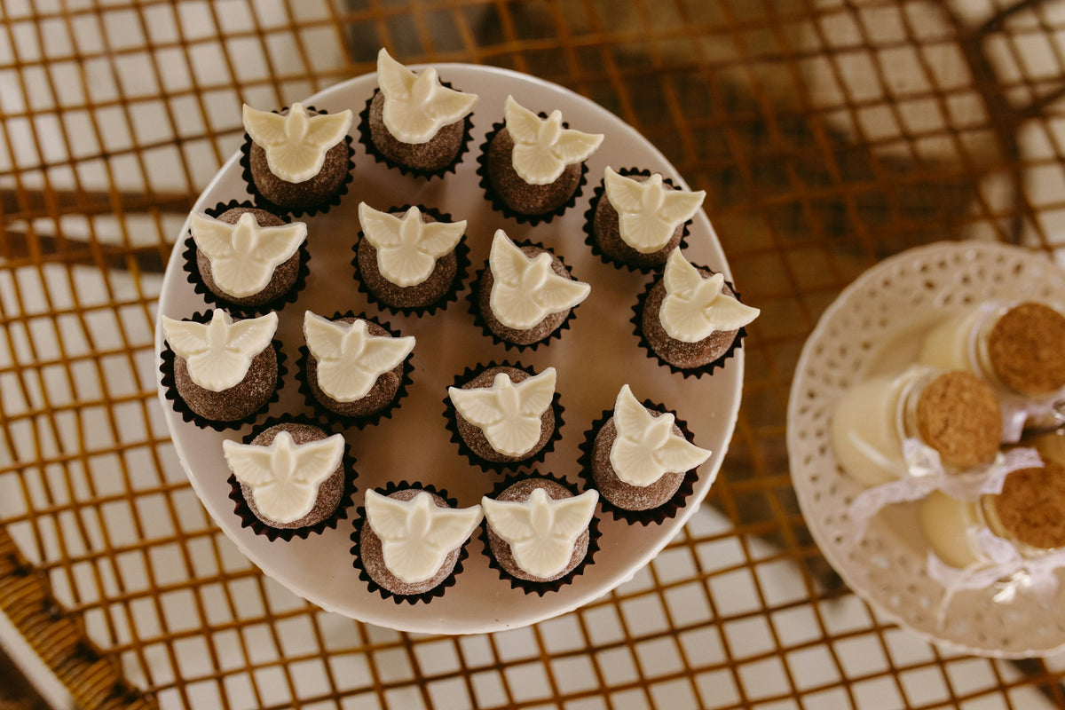 Small cakes topped with white dove decorations on a cake stand