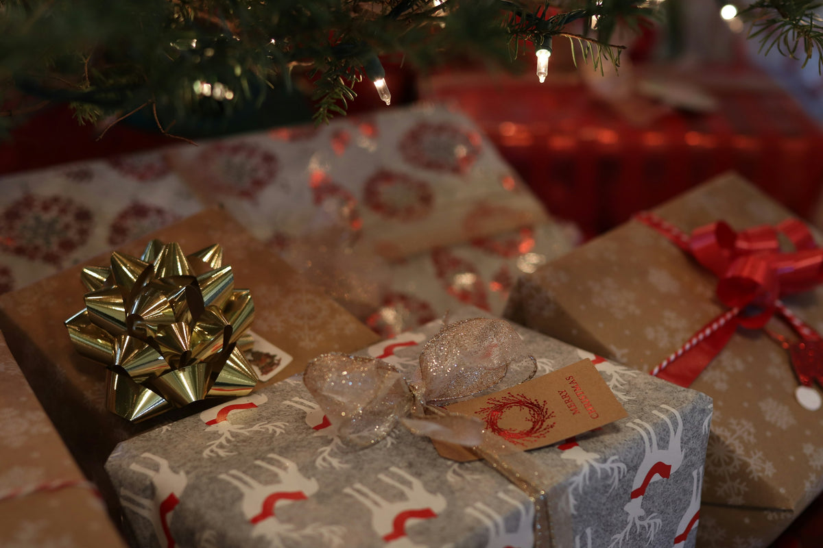 Wrapped presents with bows under a lit Christmas tree
