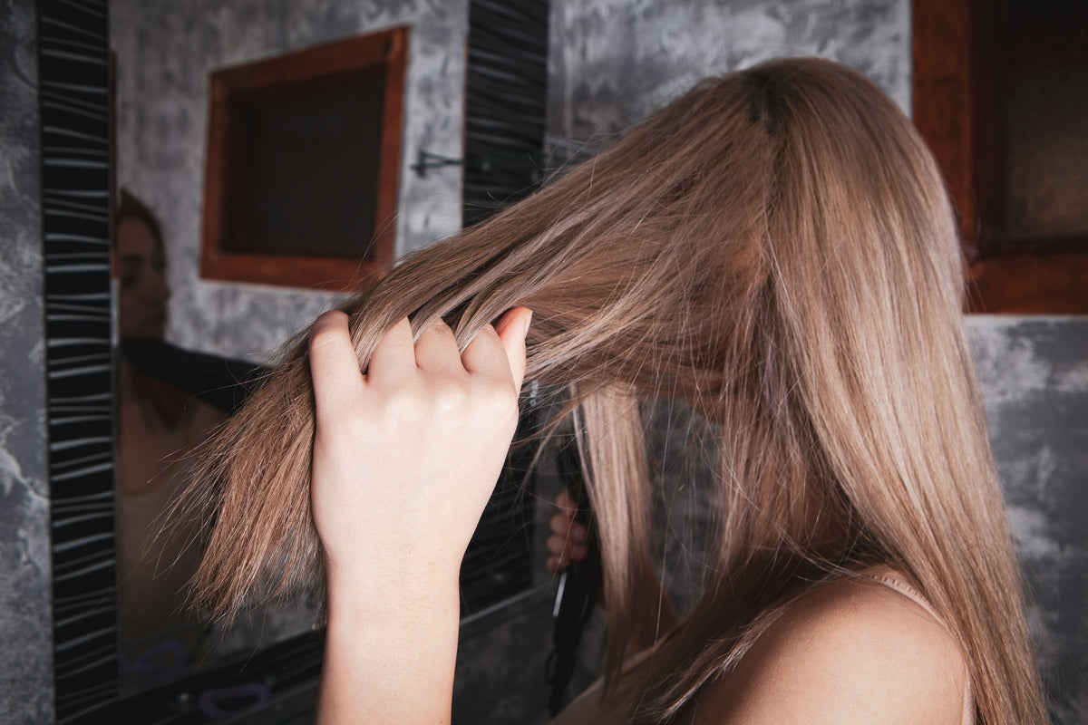 Woman styling long hair in front of a mirror