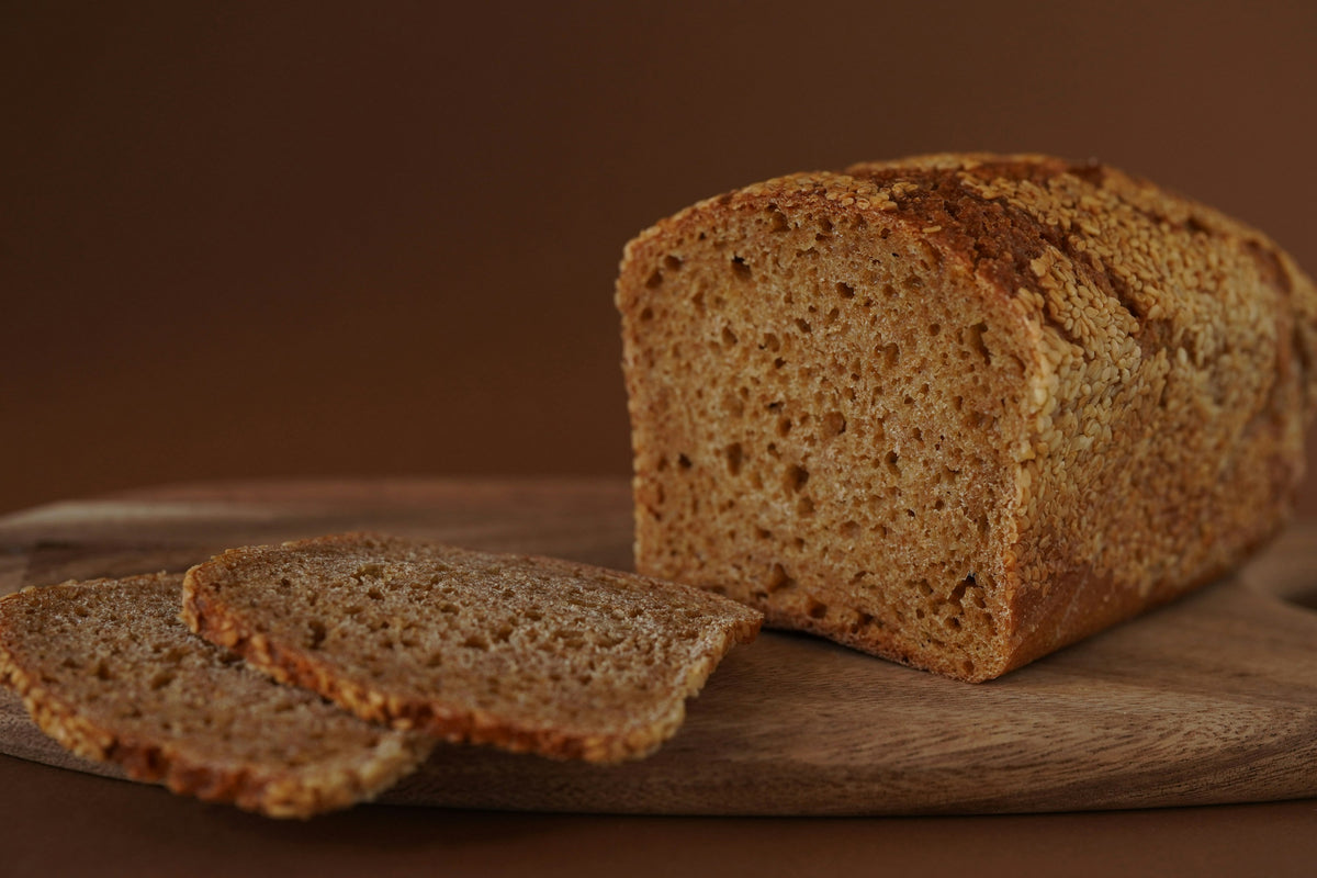 Brown bread loaf and two slices on a wooden board