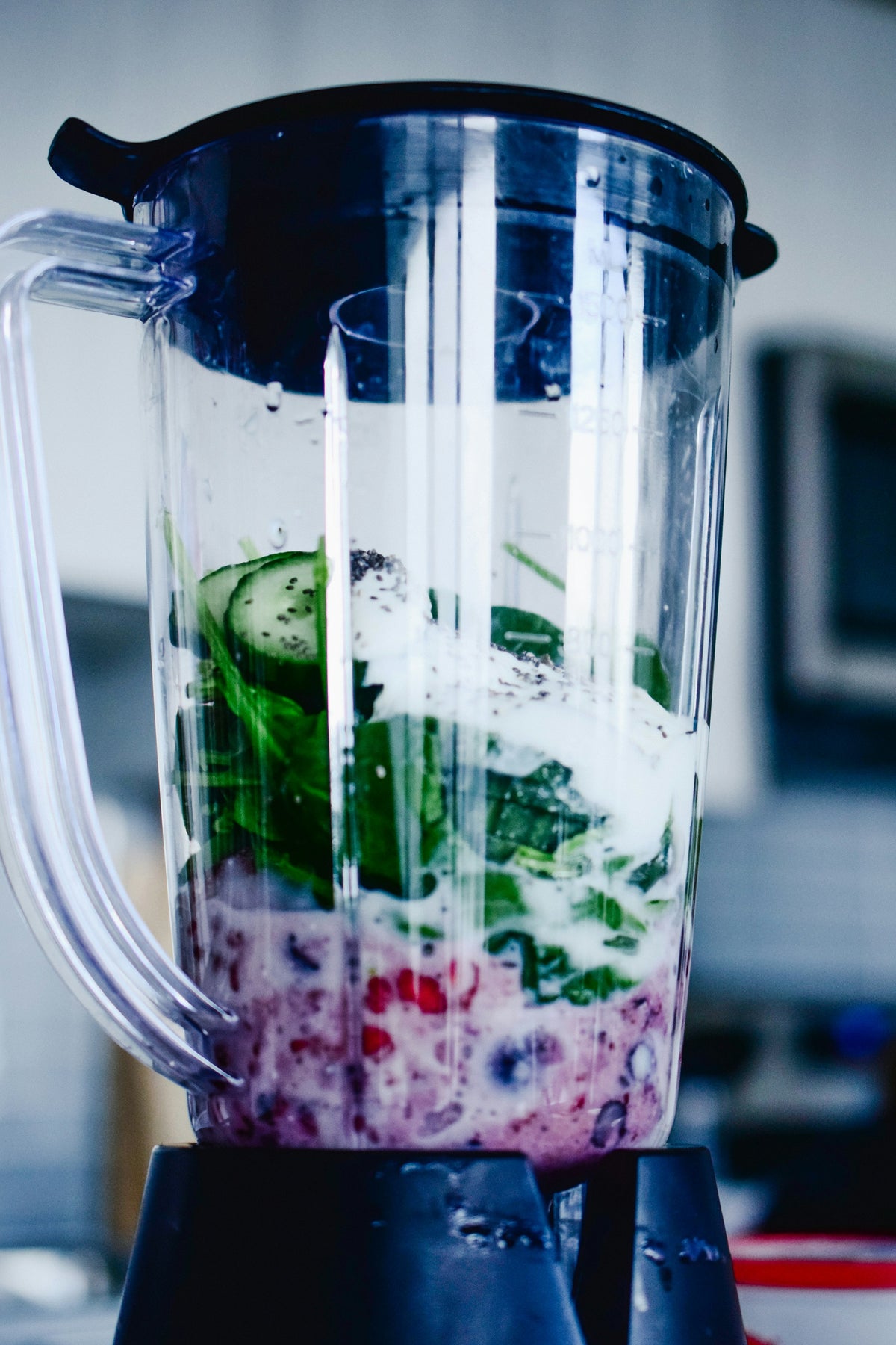 Spinach, cucumber, berries and yoghurt in a blender jug