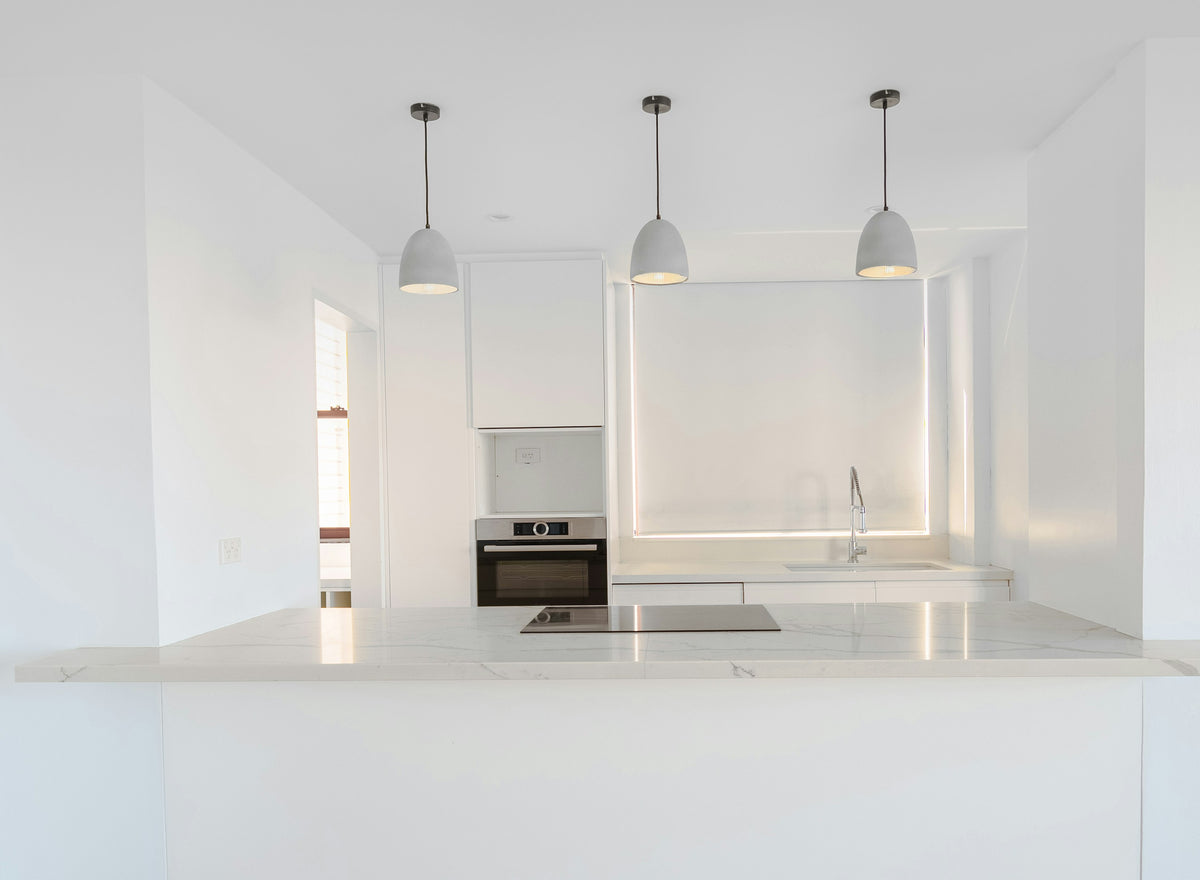 White kitchen with a built-in oven and a black induction hob set into a marble-effect island