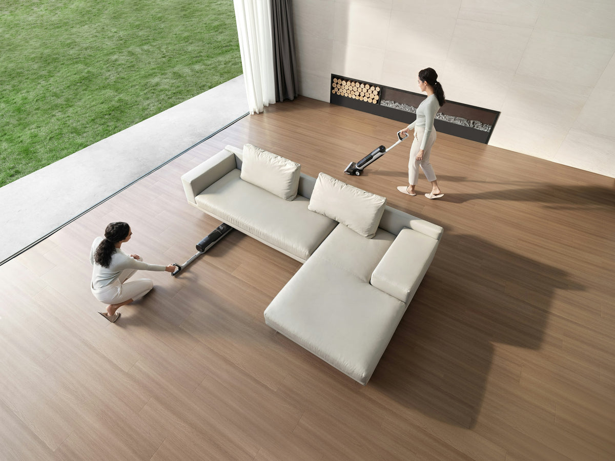 Two women cleaning a bright living room with cordless floor cleaners, seen from above